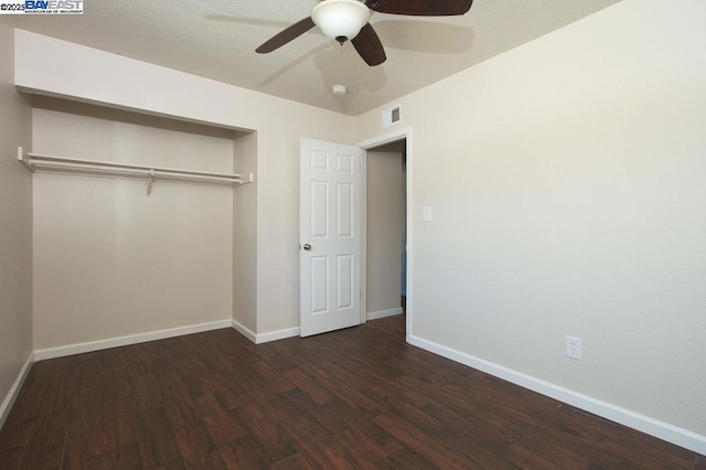 unfurnished bedroom with ceiling fan, dark wood-type flooring, and a closet