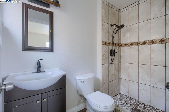 bathroom featuring toilet, vanity, and a tile shower