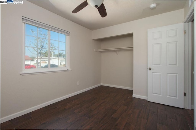 unfurnished bedroom featuring ceiling fan, a closet, and dark wood-type flooring