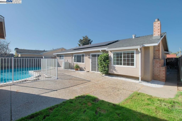 back of house with a patio area, solar panels, and a fenced in pool