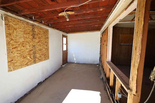 interior space with concrete floors, wooden ceiling, and wood walls