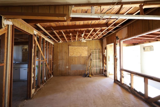 basement with ceiling fan and wood walls