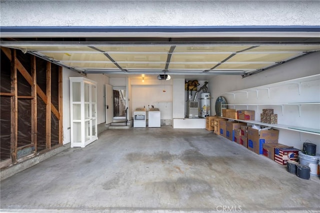 garage featuring a garage door opener, washer and dryer, and strapped water heater