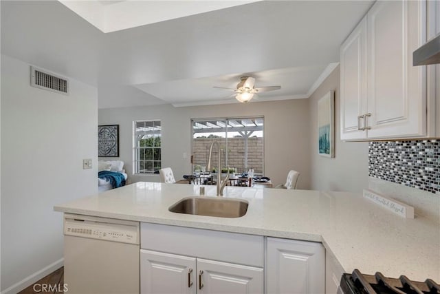 kitchen with ceiling fan, decorative backsplash, sink, white dishwasher, and white cabinetry