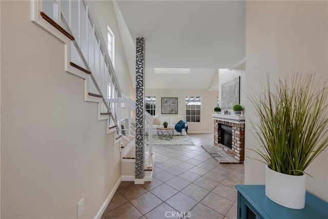 tiled foyer entrance featuring vaulted ceiling and a brick fireplace