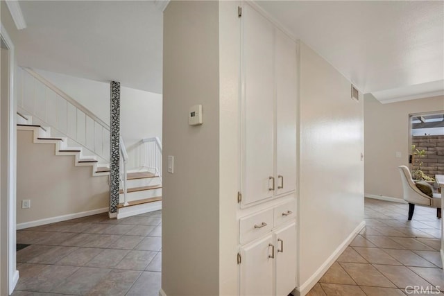 corridor with light tile patterned floors and ornamental molding