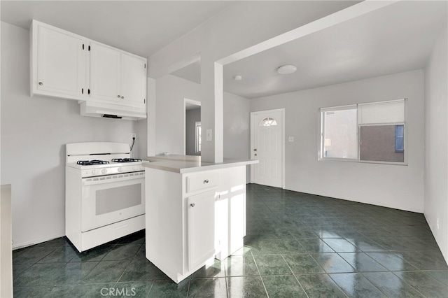 kitchen with white cabinetry, white gas range, kitchen peninsula, and dark tile patterned flooring