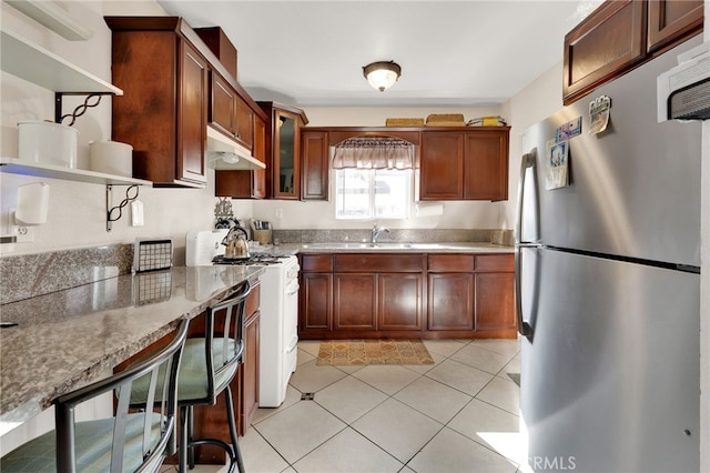 kitchen featuring sink, light tile patterned flooring, white range with gas cooktop, light stone countertops, and stainless steel fridge