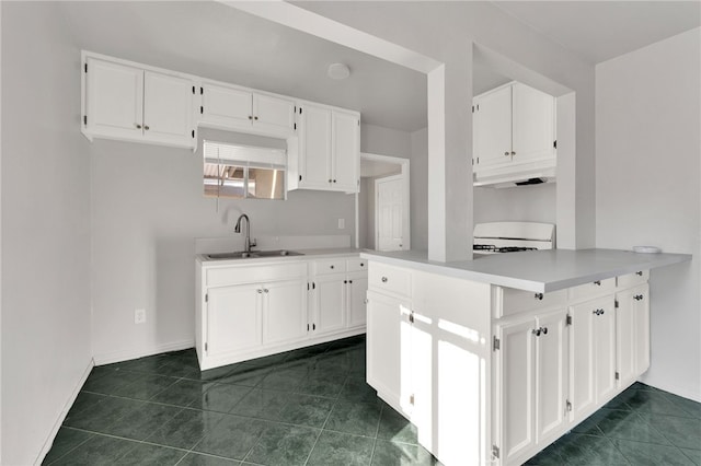 kitchen featuring sink, white cabinetry, range, and kitchen peninsula