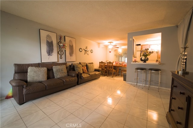 living room with a textured ceiling, ceiling fan, and light tile patterned flooring