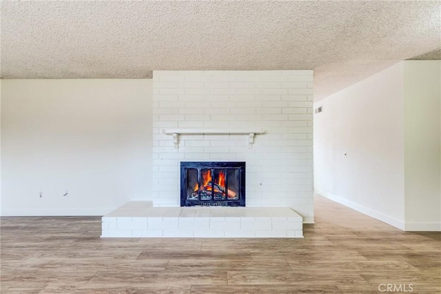 interior details featuring wood-type flooring, a brick fireplace, and a textured ceiling