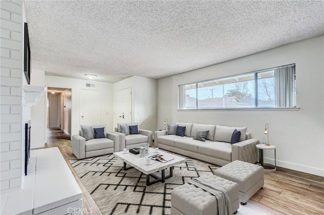 living room featuring a fireplace, light hardwood / wood-style floors, and a textured ceiling