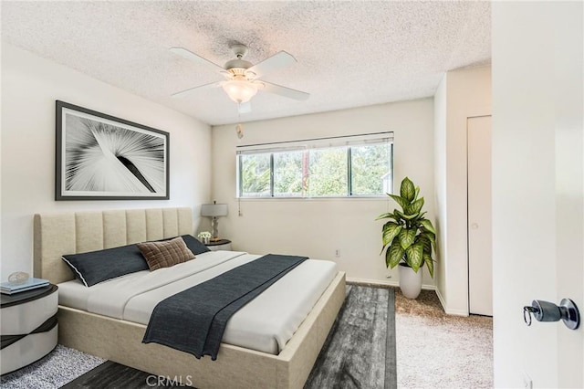 carpeted bedroom with ceiling fan and a textured ceiling