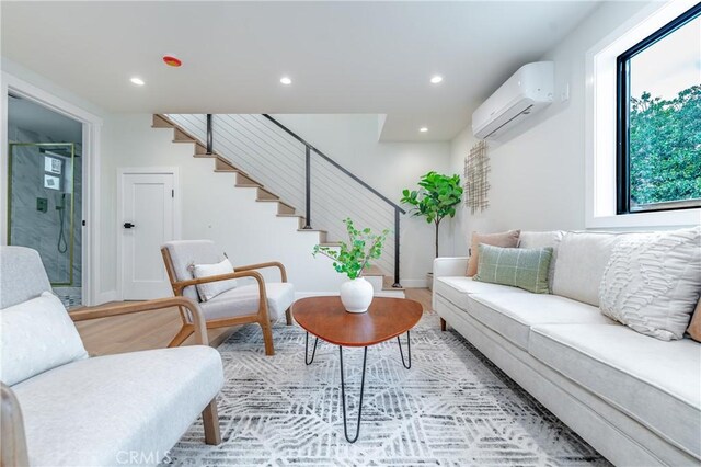 living room featuring light hardwood / wood-style flooring, a wealth of natural light, and a wall mounted AC