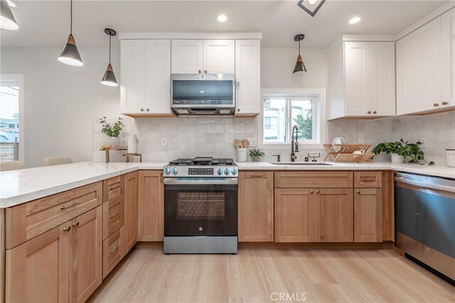 kitchen featuring pendant lighting, sink, appliances with stainless steel finishes, white cabinets, and decorative backsplash