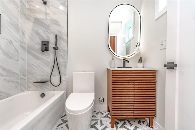 full bathroom featuring vanity, tiled shower / bath, and toilet