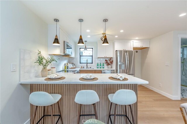 kitchen featuring appliances with stainless steel finishes, sink, white cabinets, decorative backsplash, and kitchen peninsula