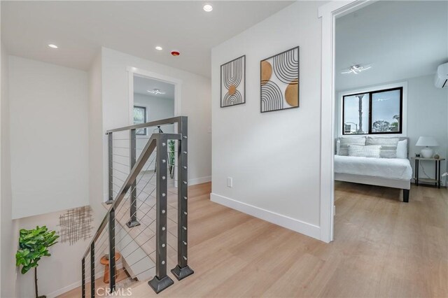 hall with light hardwood / wood-style flooring and a wall mounted AC