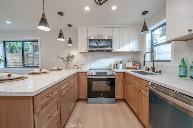 kitchen with decorative light fixtures, sink, white cabinets, stainless steel appliances, and light stone countertops