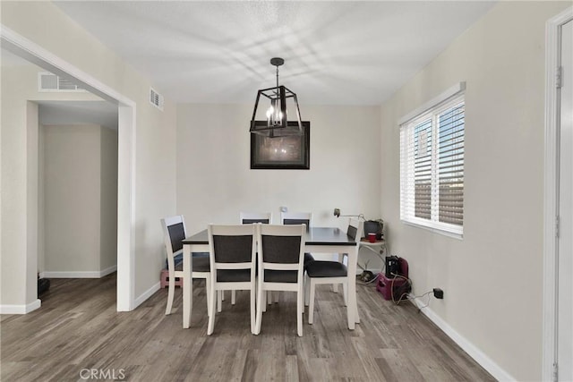 dining space featuring hardwood / wood-style flooring and a chandelier