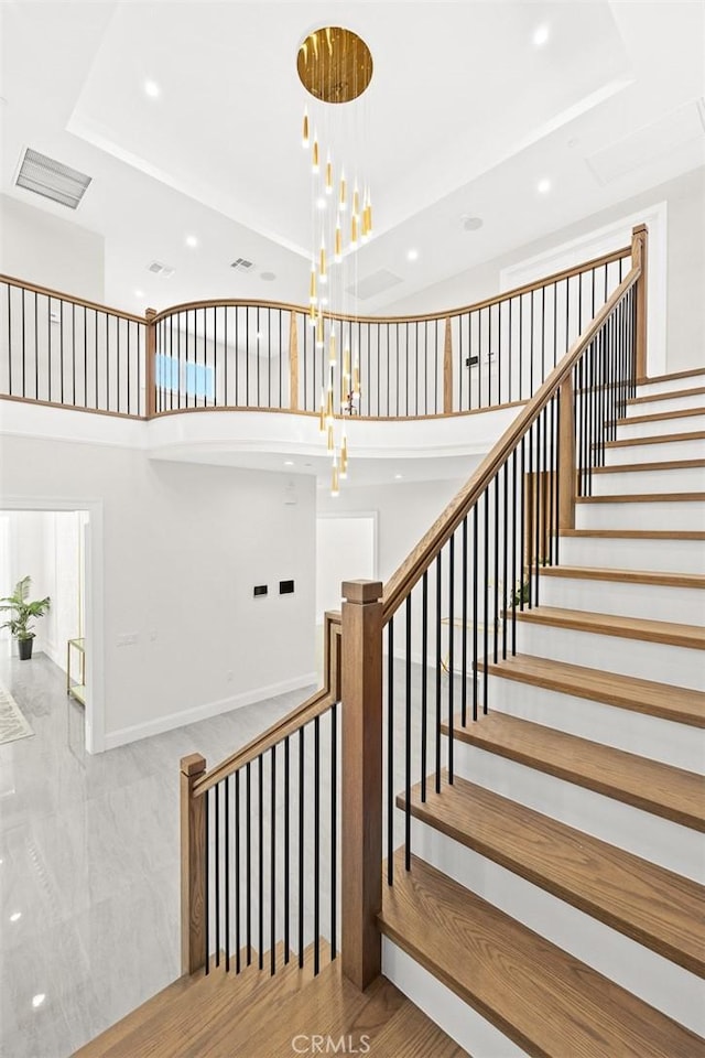 stairs with an inviting chandelier, a high ceiling, and hardwood / wood-style floors