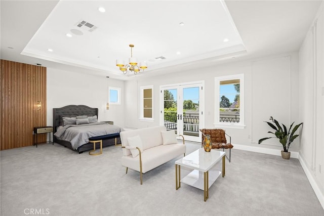 bedroom with light colored carpet, access to exterior, a tray ceiling, and a chandelier