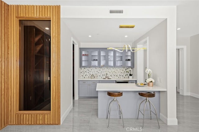 bar featuring gray cabinets, dishwashing machine, backsplash, decorative light fixtures, and sink