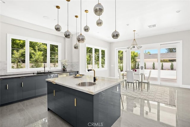 kitchen with hanging light fixtures, a kitchen island with sink, dishwasher, and sink