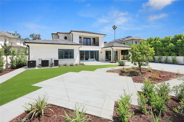 rear view of property with central AC unit and a lawn