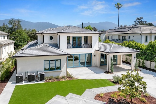 back of property featuring a lawn, central AC, a mountain view, and a balcony