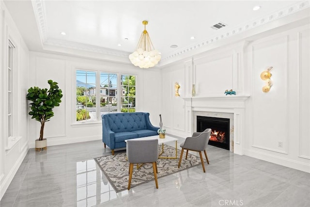 living area with a high end fireplace, crown molding, and a tray ceiling