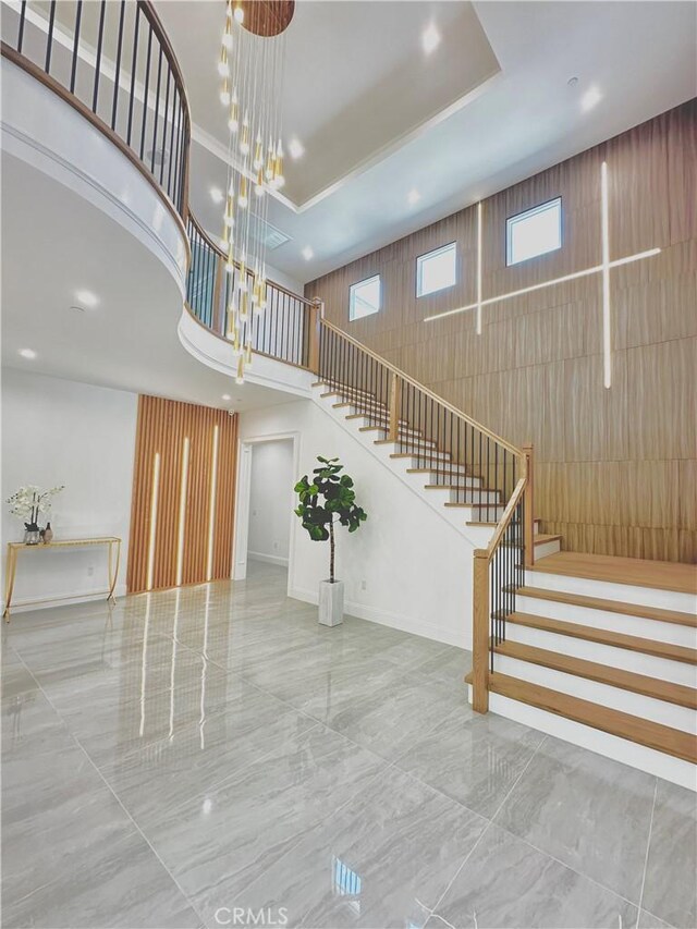 stairway featuring a towering ceiling, a tray ceiling, and a notable chandelier