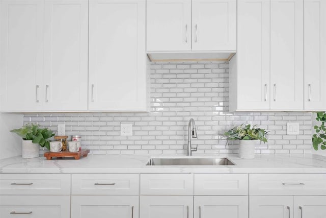 kitchen with tasteful backsplash, sink, and white cabinetry