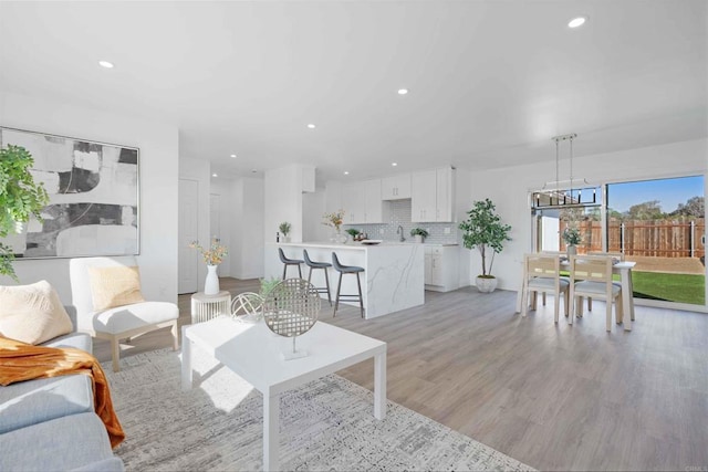 living room featuring a notable chandelier, sink, and light hardwood / wood-style floors