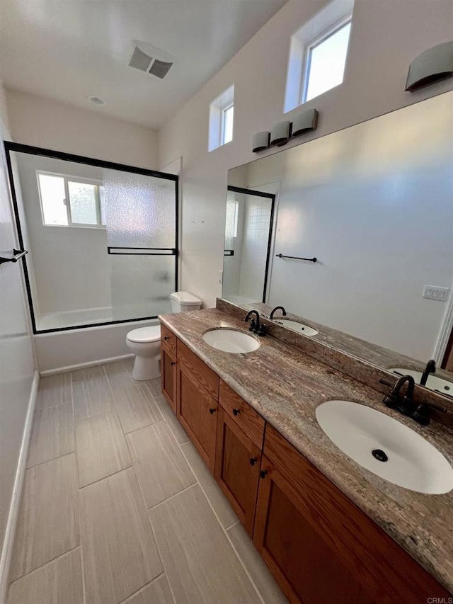 full bathroom featuring plenty of natural light, shower / bath combination with glass door, vanity, and toilet