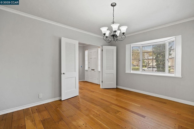 unfurnished room with ornamental molding, a chandelier, and hardwood / wood-style flooring