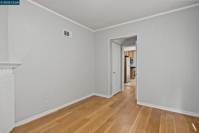 empty room featuring ornamental molding and light wood-type flooring