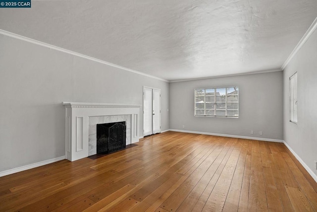 unfurnished living room featuring hardwood / wood-style floors, a tile fireplace, and crown molding