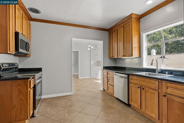 kitchen with light tile patterned floors, stainless steel appliances, dark stone counters, ornamental molding, and sink