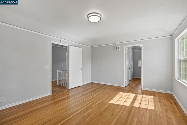 empty room featuring ornamental molding and light hardwood / wood-style flooring