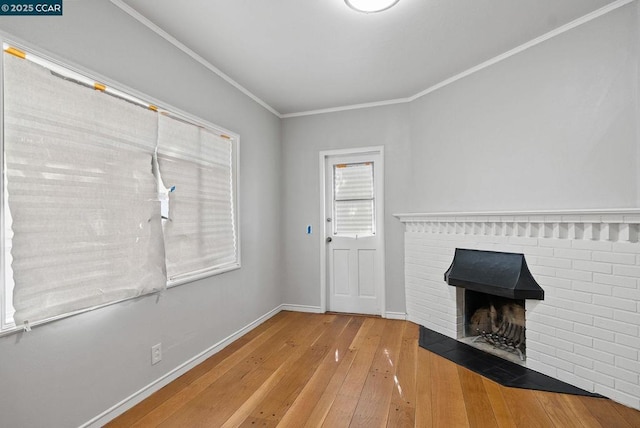 interior space with a brick fireplace, ornamental molding, and hardwood / wood-style floors