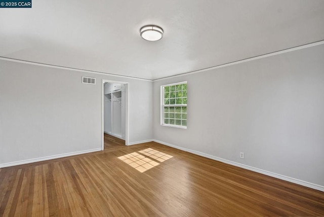 unfurnished room with hardwood / wood-style flooring and ornamental molding