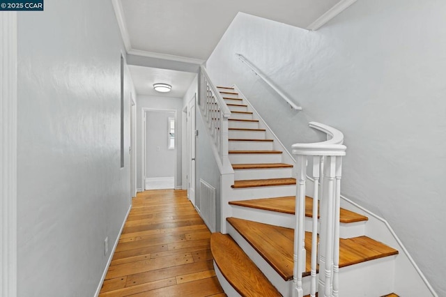 stairs with hardwood / wood-style flooring and crown molding