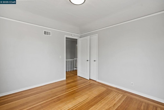 empty room featuring hardwood / wood-style floors and ornamental molding