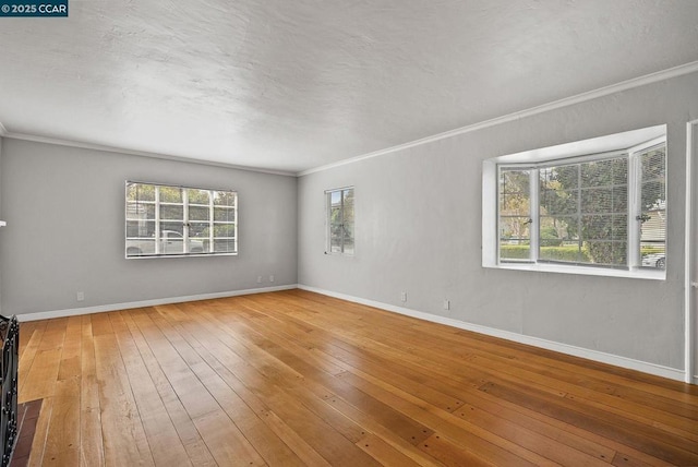 spare room featuring wood-type flooring, plenty of natural light, and crown molding