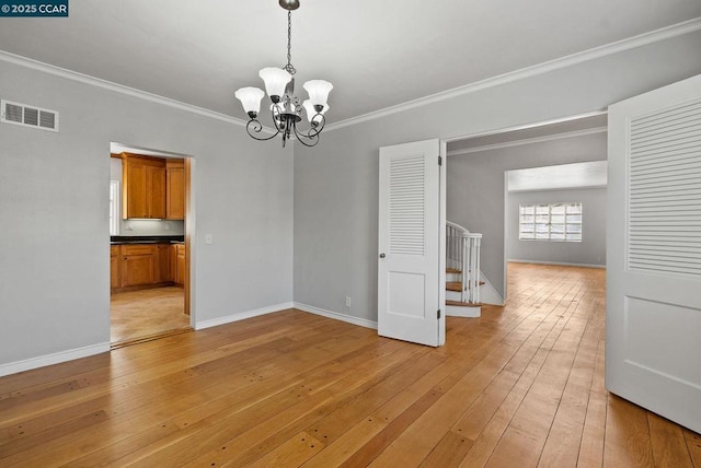 empty room featuring a chandelier, crown molding, and light hardwood / wood-style flooring