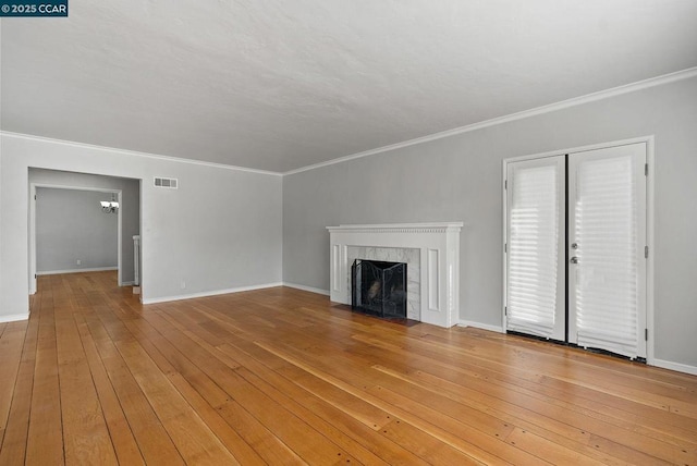 unfurnished living room with an inviting chandelier, ornamental molding, wood-type flooring, and a tile fireplace