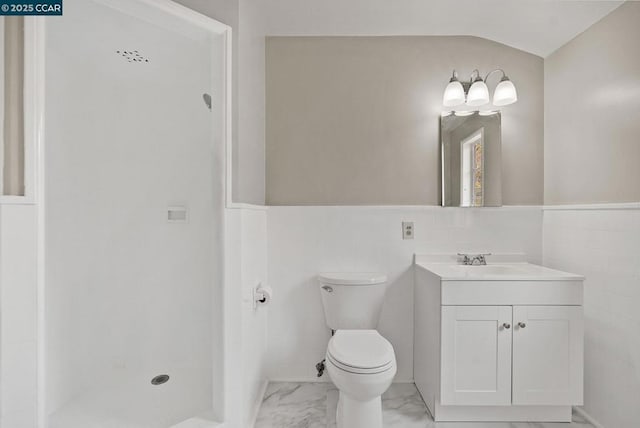 bathroom with toilet, vaulted ceiling, vanity, and tile walls