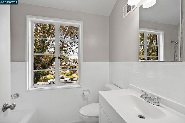 bathroom featuring toilet, vaulted ceiling, plenty of natural light, and vanity