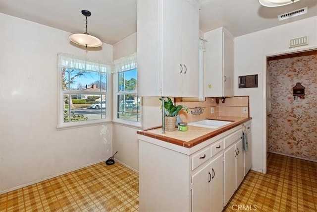 kitchen with decorative backsplash, sink, pendant lighting, and white cabinets